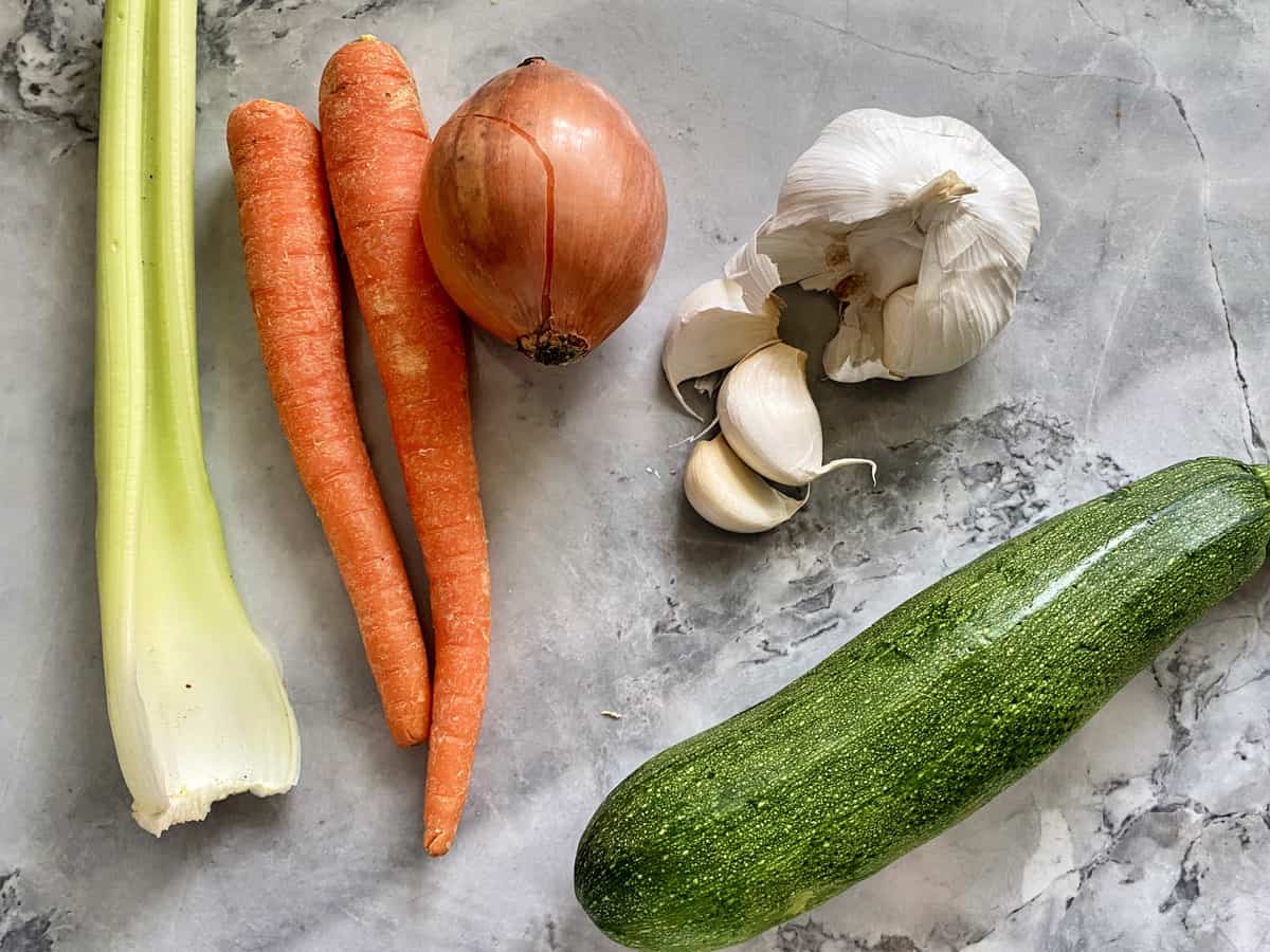 Ingredients on counter: celery, carrots, onion, garlic, and zucchini.