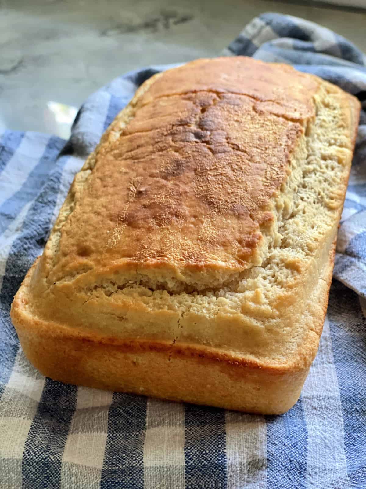 whole loaf of golden brown Beer Bread resting on tablecloth.