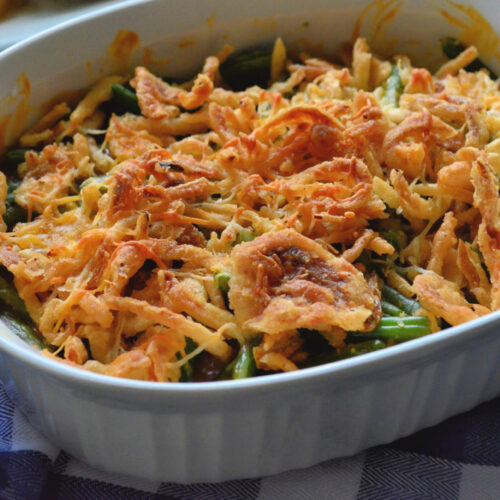 Golden Green Bean Casserole in casserole dish topped with melted cheese and crispy onions.