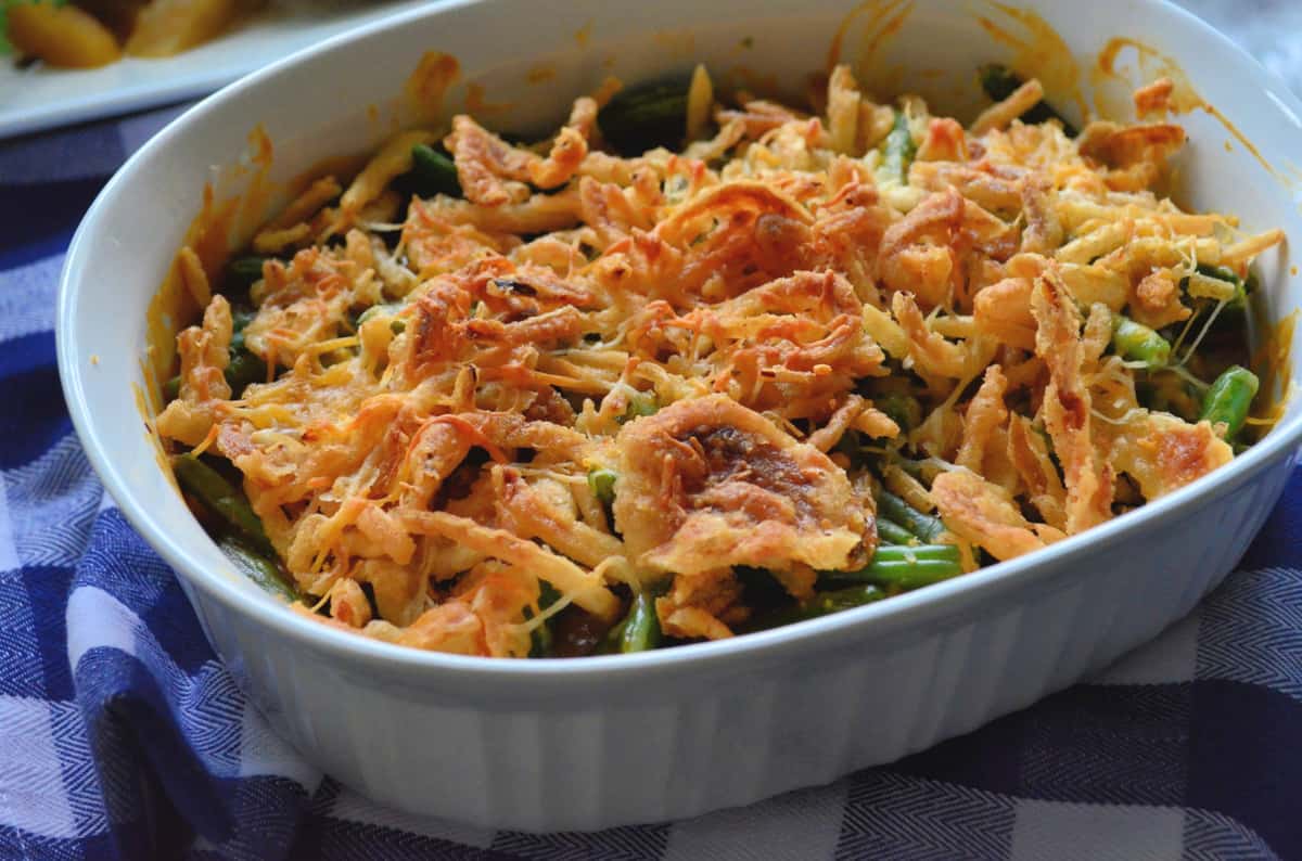 Golden Green Bean Casserole in a baking dish on a blue and white checkered cloth.