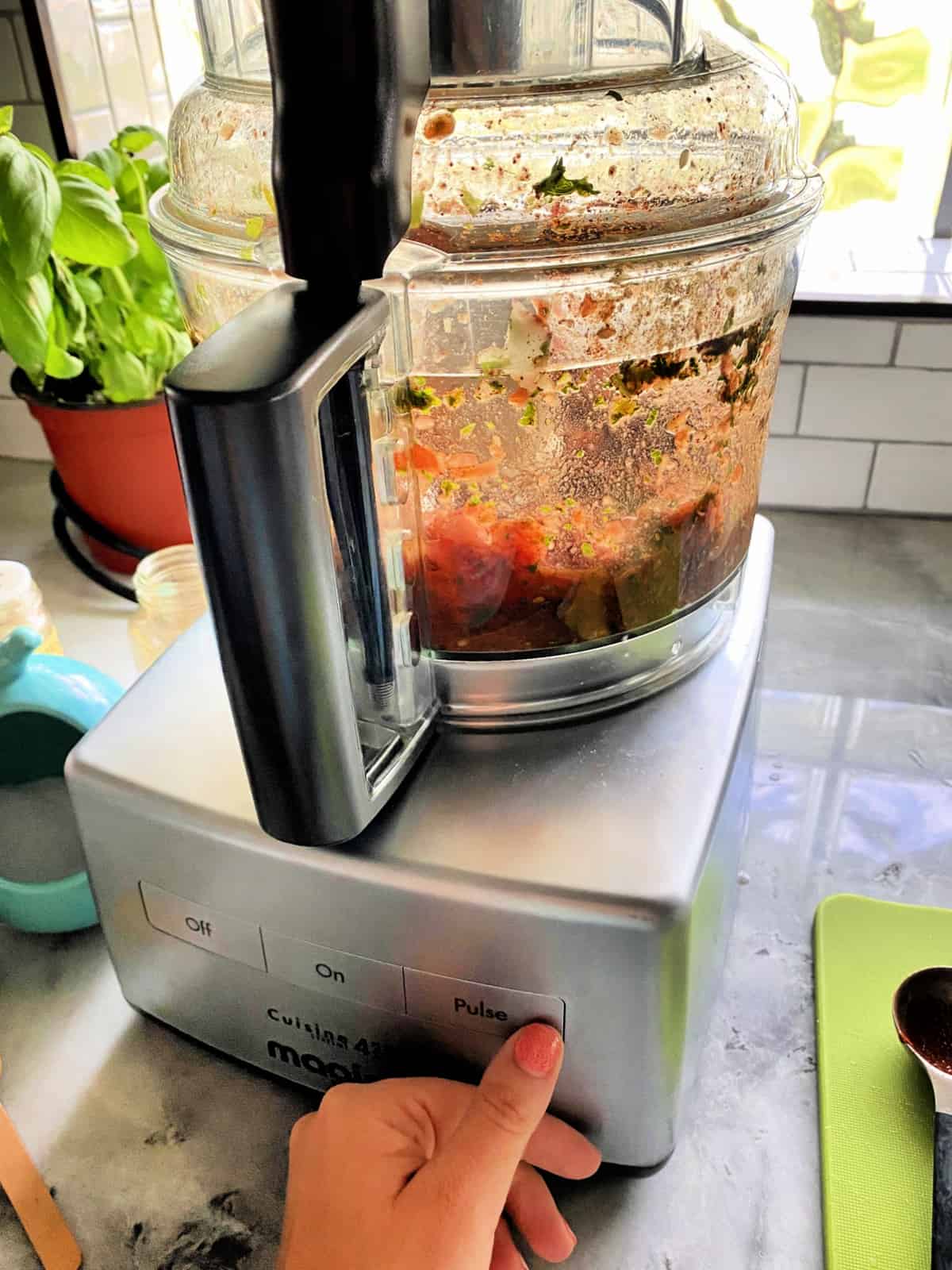 Food processor with blended salsa in it.