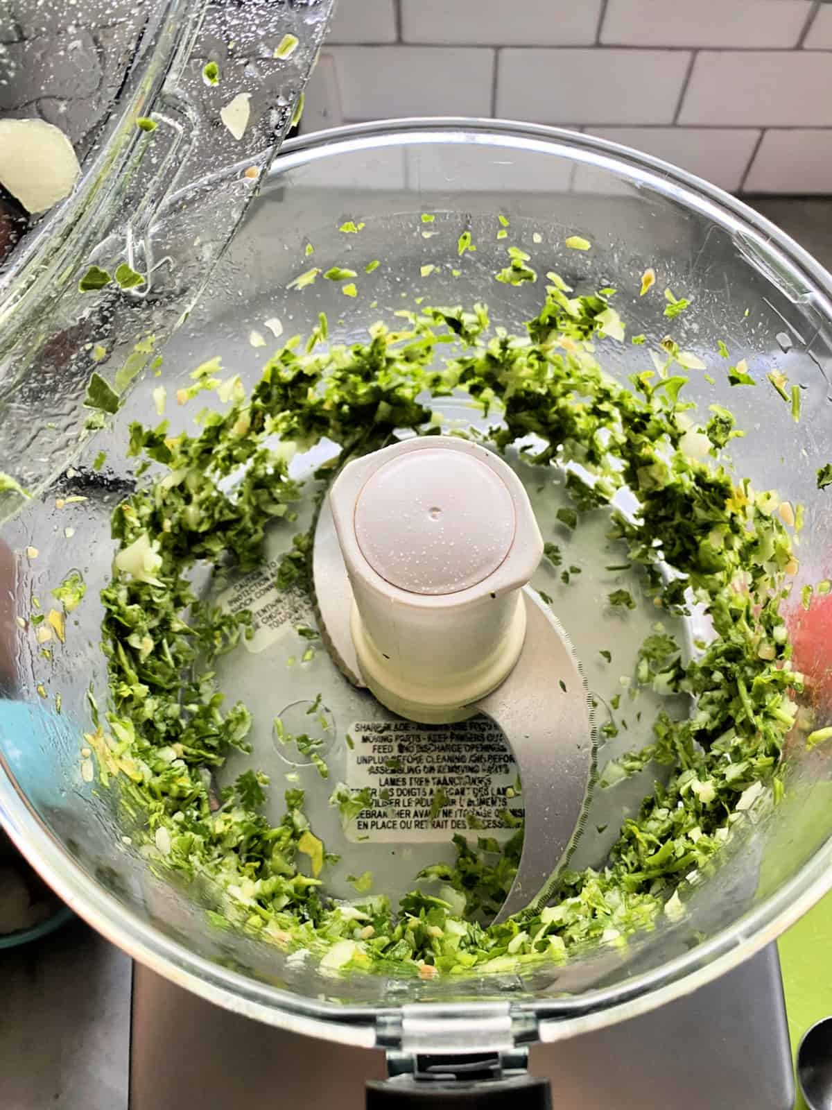 Food processor with blended cilantro and onion.