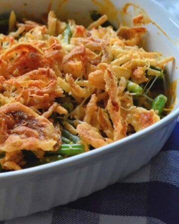 Golden Green Bean Casserole in casserole dish topped with melted cheese and crispy onions.
