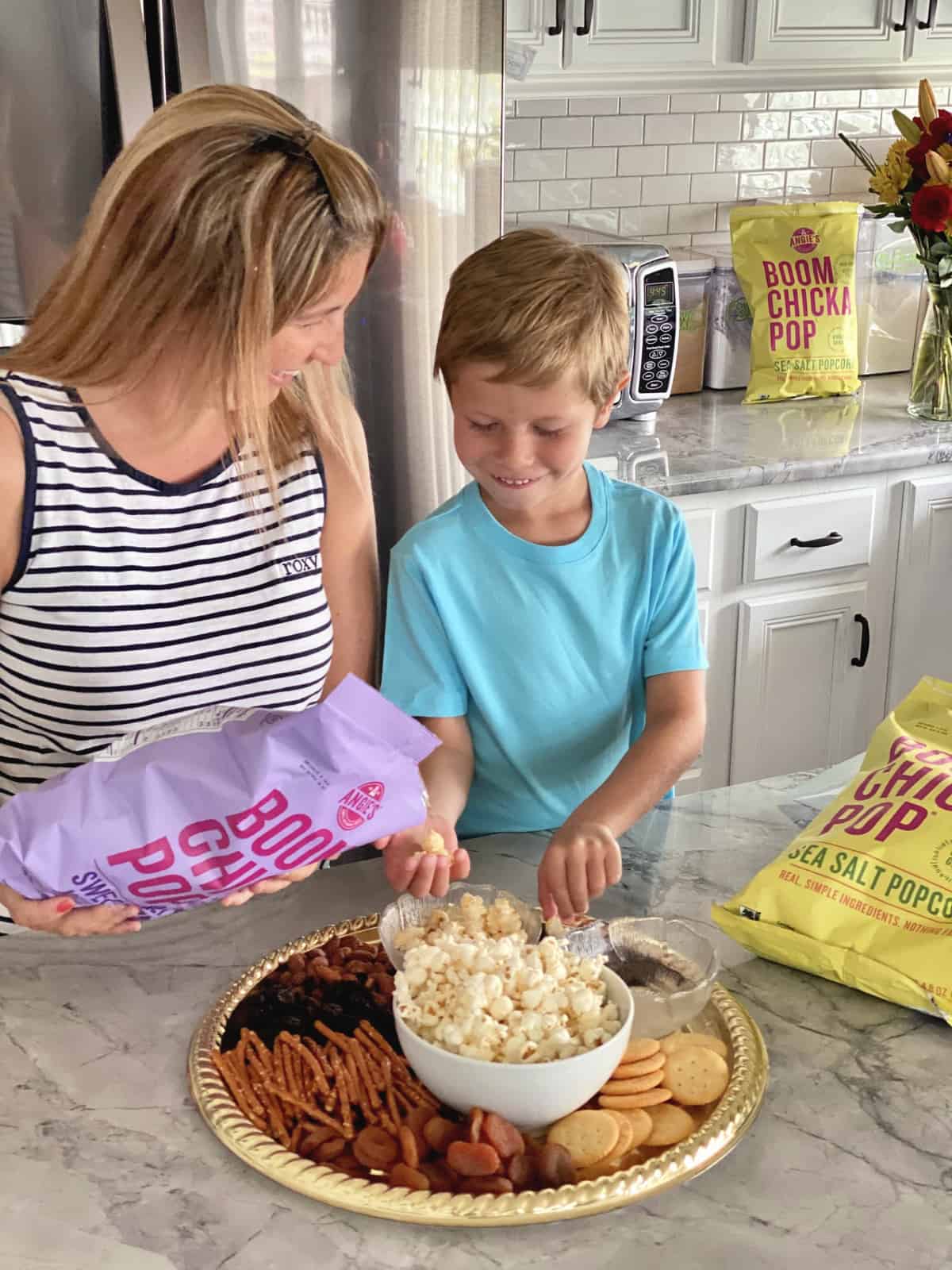 Pouring Angie’s BOOMCHICKAPOP Sweet & Salty Kettle Corn and son catching it in his hand.