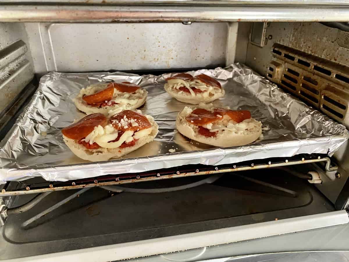 English Muffin Pizzas on aluminum foil covered pan in the toaster oven.