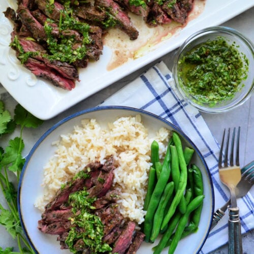 Plated Grilled Skirt stake over bed of white rice with green beans.