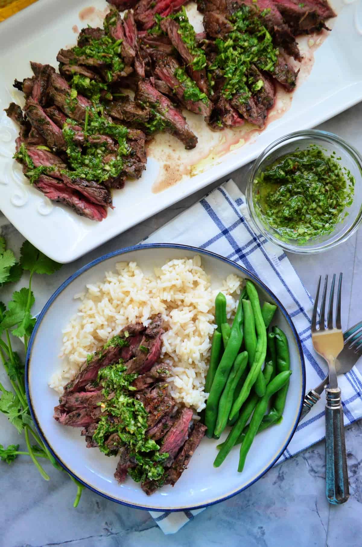 Plated Grilled Skirt stake over bed of white rice with green beans.