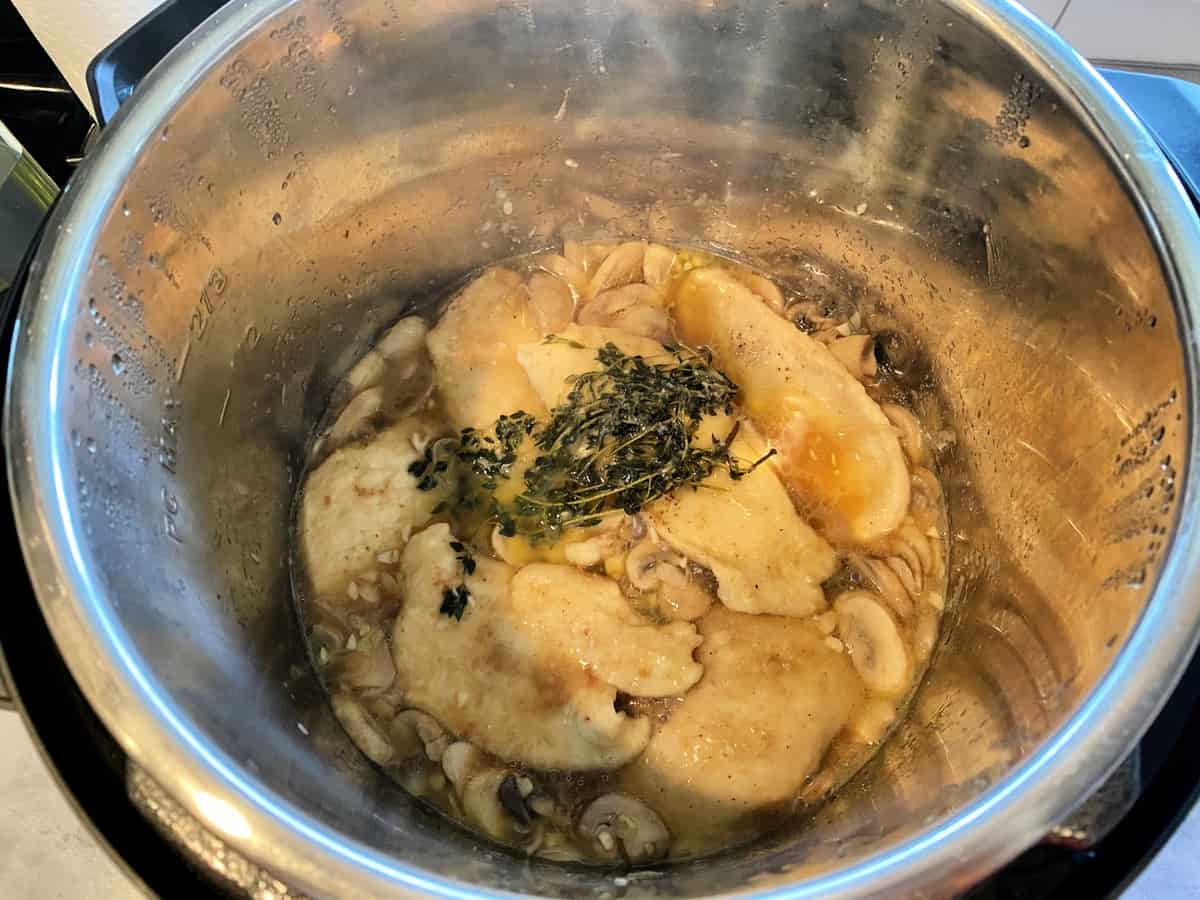 Cooked chicken cutlets for Chicken Marsala in the Instant Pot with mushrooms and thyme.