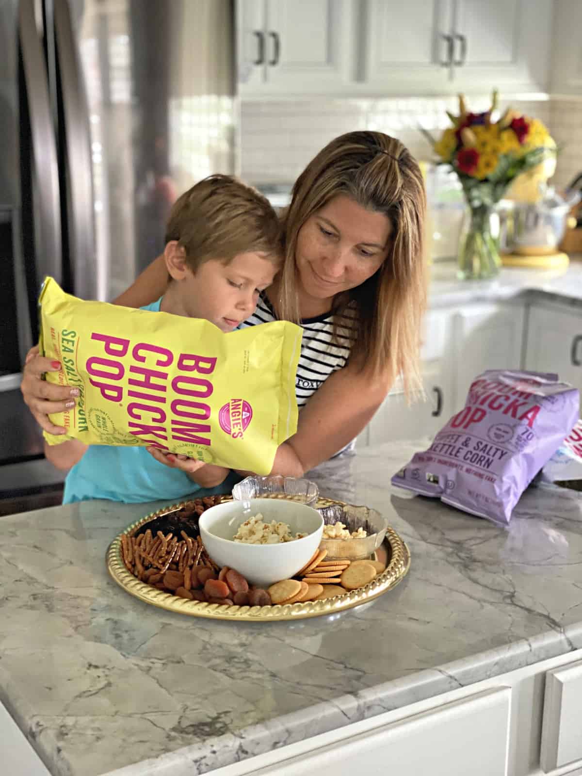 Mother and Son at kitchen counter putting together Snack Board by adding popcorn.