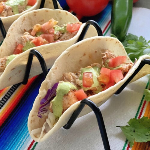 3 Blackened Swordfish Tacos on Black Metal Wire Taco Holder garnished with Cilantro.