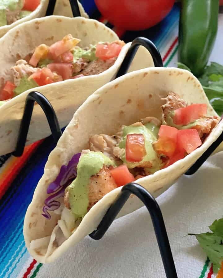 3 Blackened Swordfish Tacos on Black Metal Wire Taco Holder garnished with Cilantro.