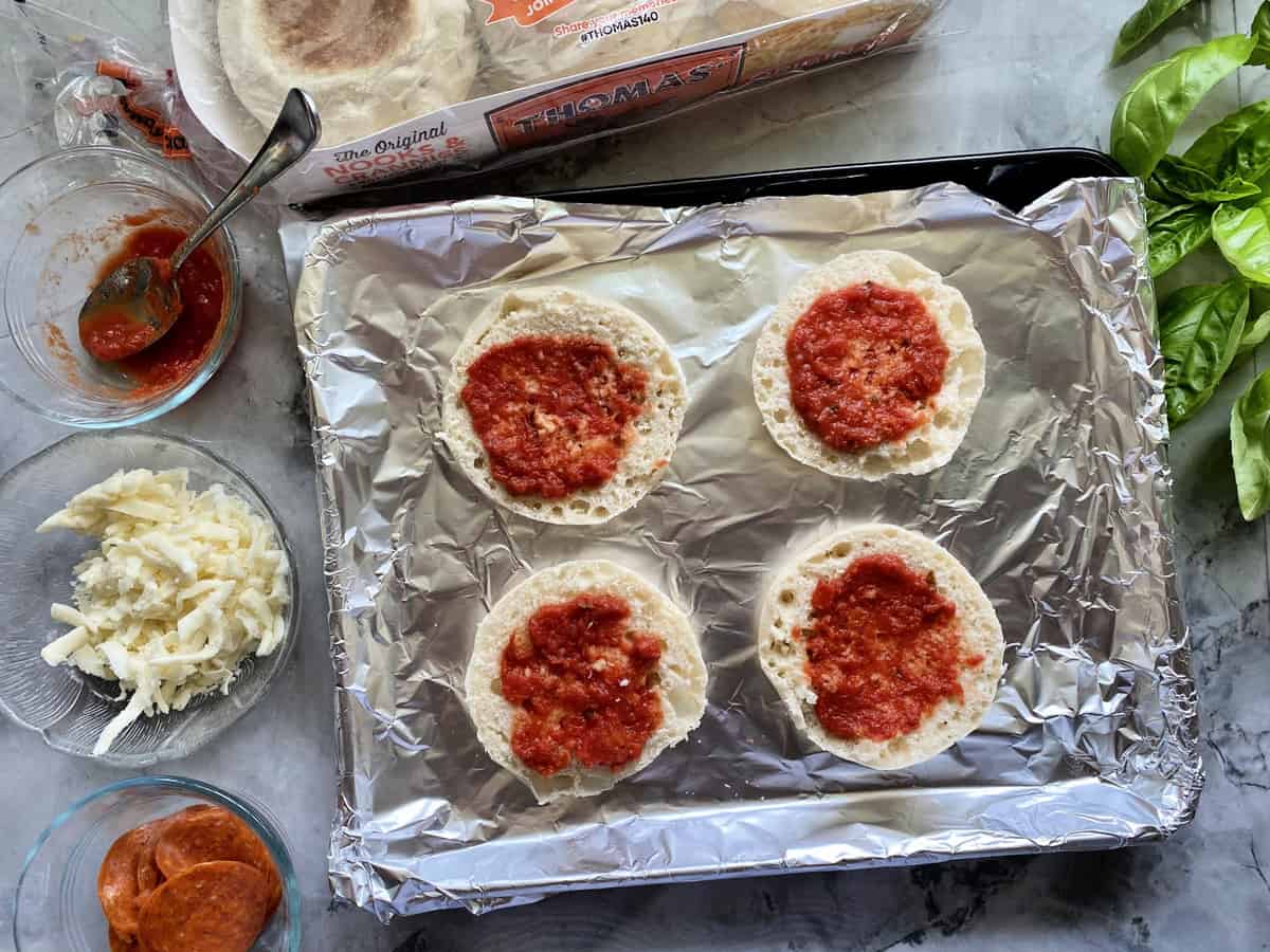 Toaster Oven English Muffin Pizzas topped with sauce. Cheese, pepperoni, & basil shown on the side.