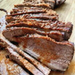 Sliced juicy brisket on a wooden cutting board.