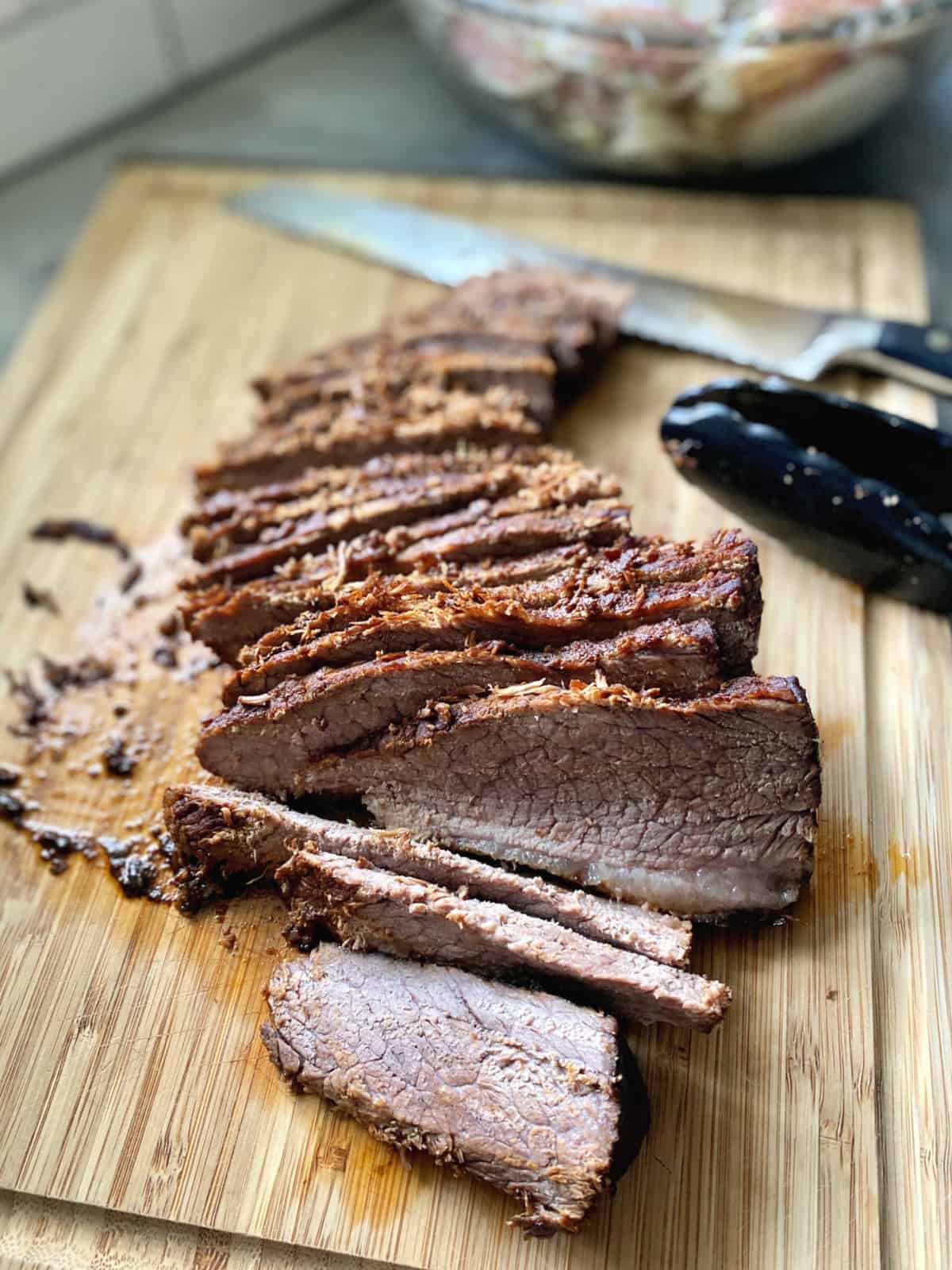 Thinly sliced pieces of beef on a wooden cutting board.