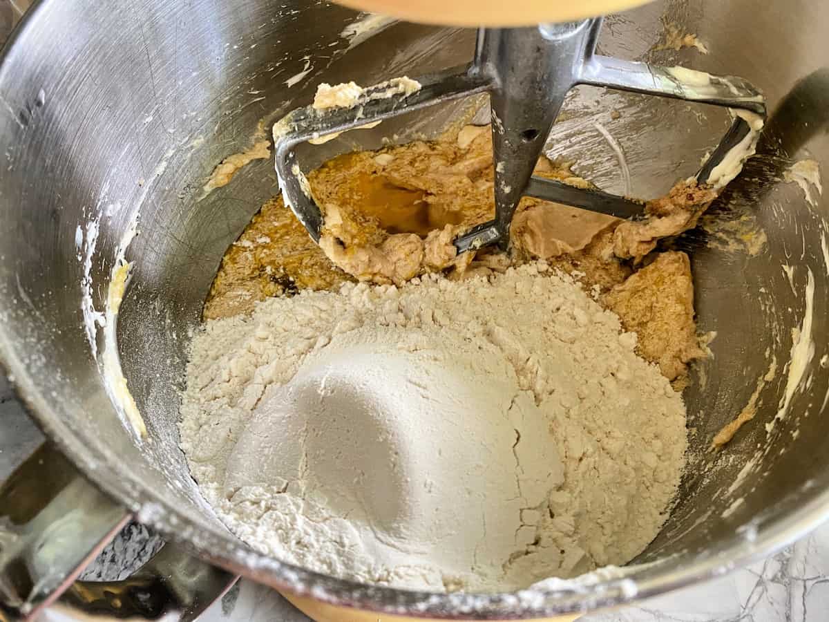 Flour, Sugar, and other dry ingredients in a stand mxier fitted with a paddle attachment.
