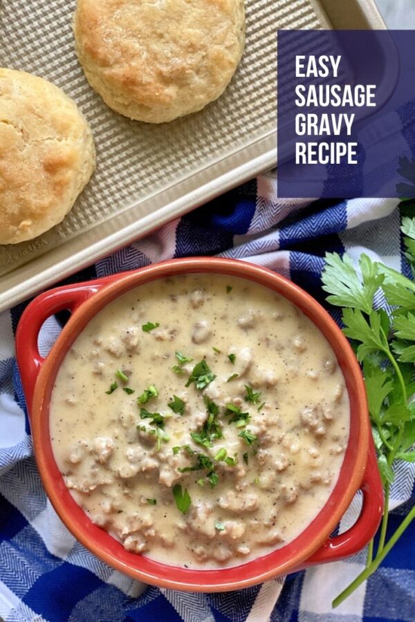 Top view of a bowl of sausage gravy with biscuits on a tray and text.