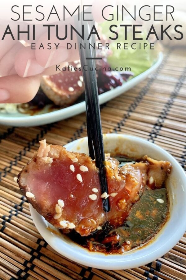 Chopsticks dipping a piece of seared tuna in a brown sauce with teext on image.