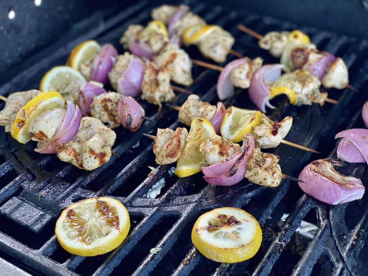 Chicken, onion and lemon wooden skewers on a grill.