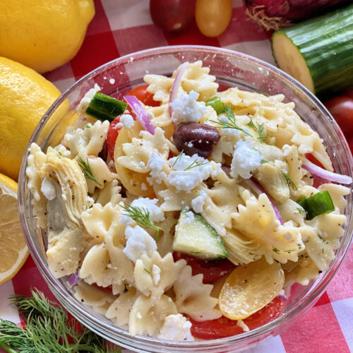 Top view of bow tie pasta salad with cucumbers, feta, dill, kalamata olives, and red onion.