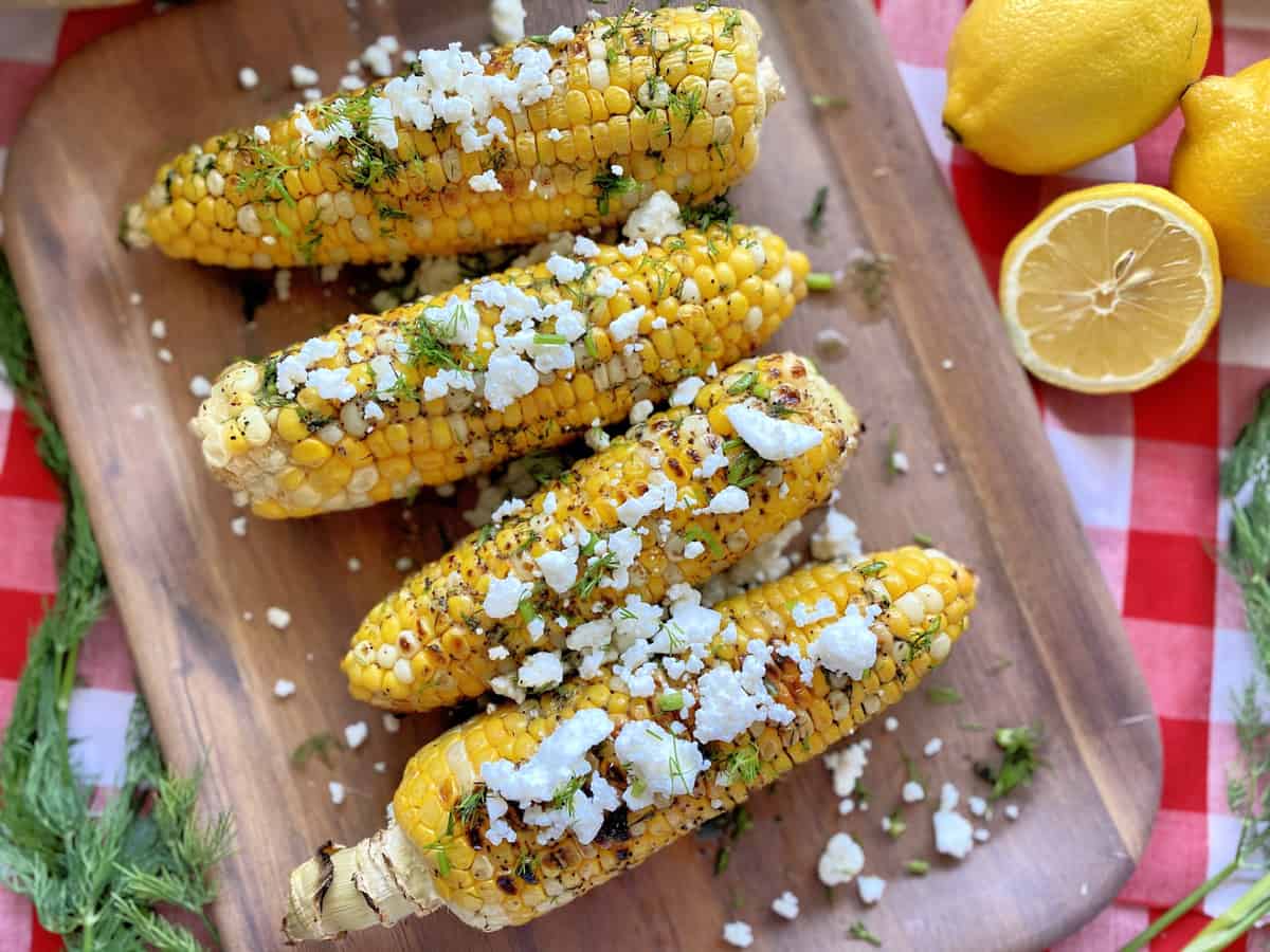 Top view of corn on the cob topped with fresh dill and feta. 