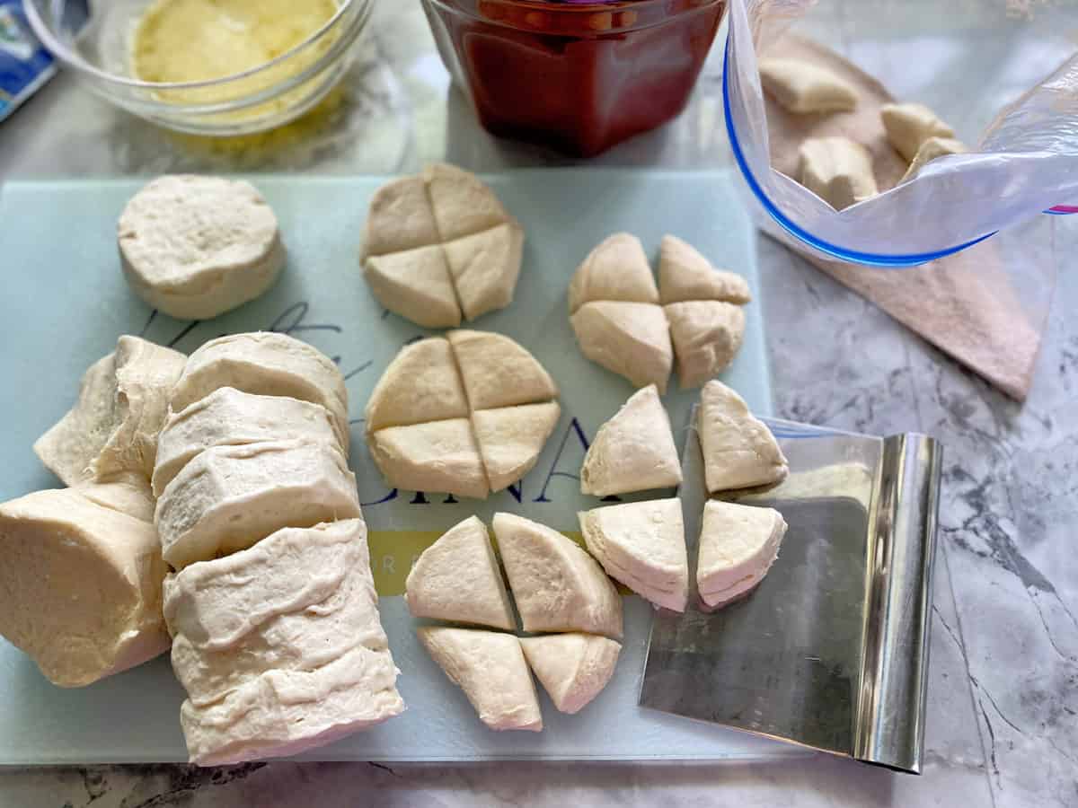 Overhead shot of cut up refrigerated canned biscuits cut into quarters.