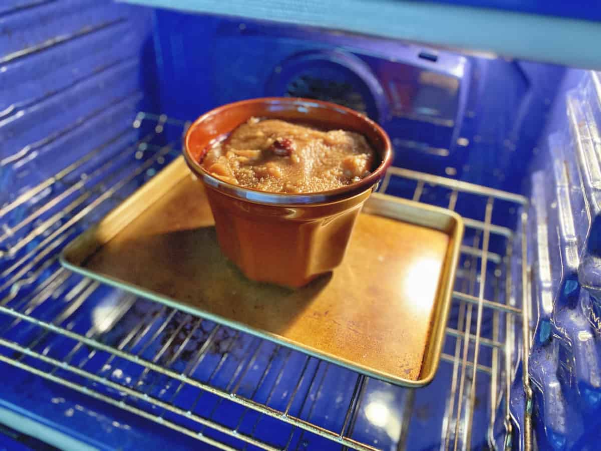 Monkey bread in a brown fluted pan on a baking dish inside a blue oven.