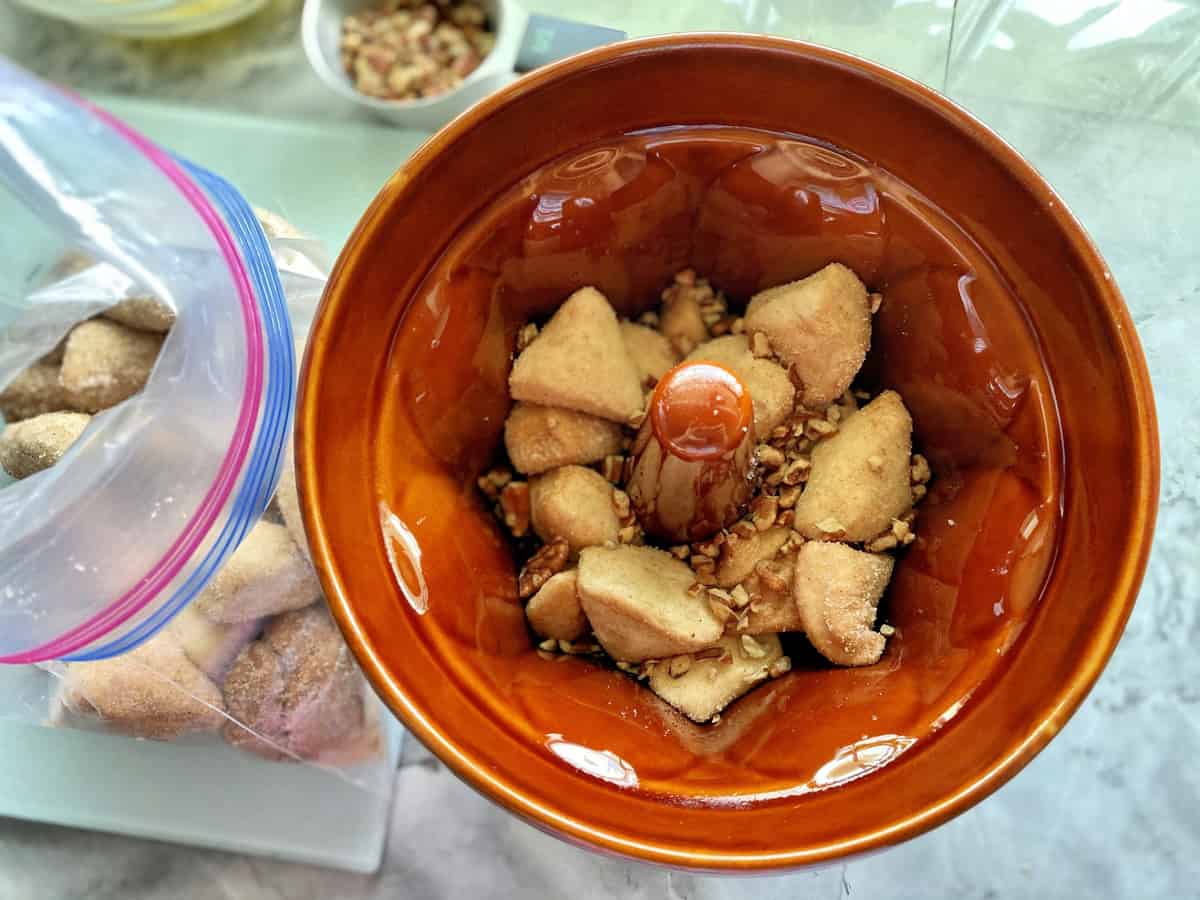 Brown fluted ceramic pan with raw cinnamon sugar biscuits with pecans. 