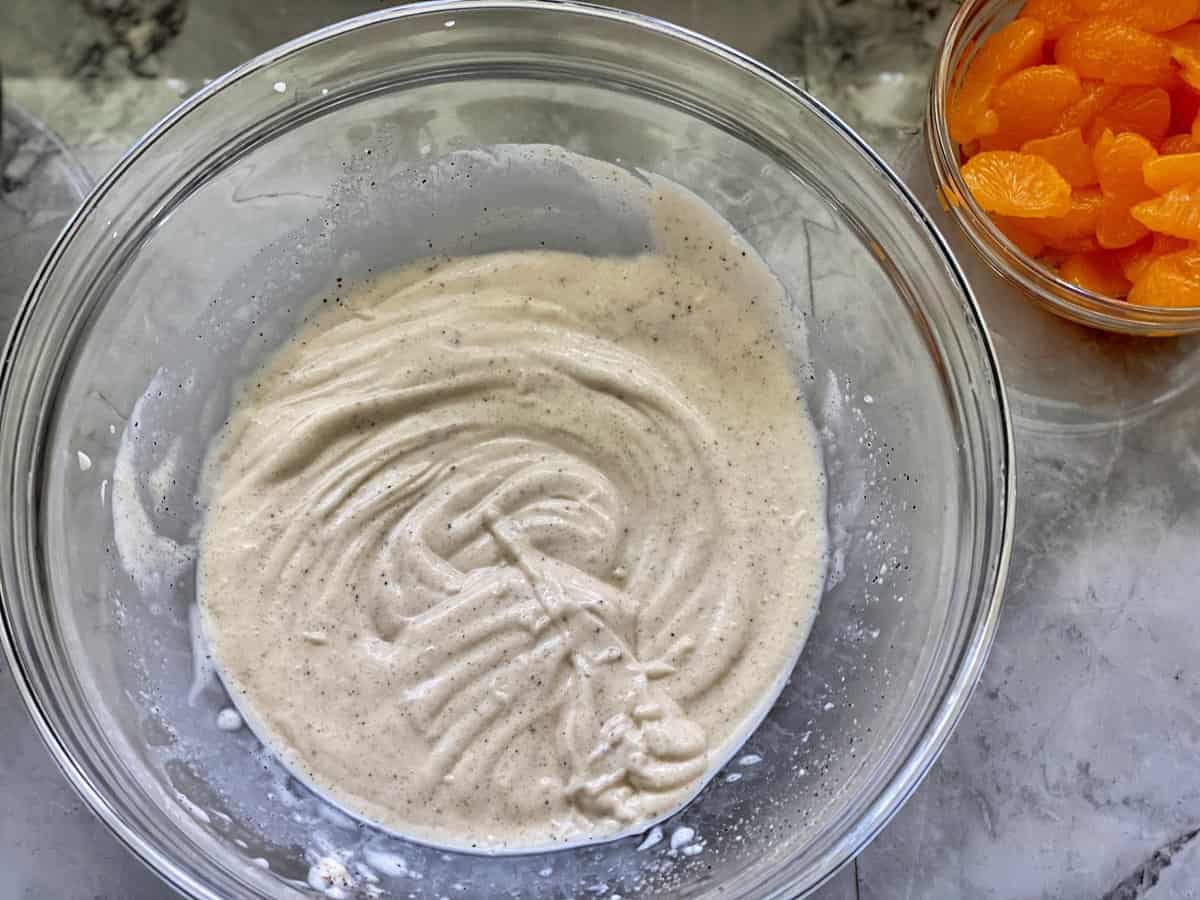 Glass bowl on marble counter with homemade coleslaw sauce well blended together.