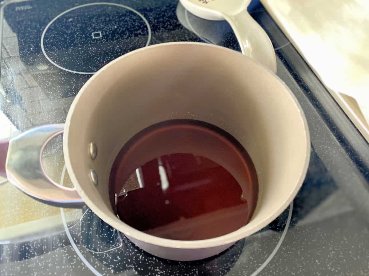 Pot on electric stove with brown syrup inside.