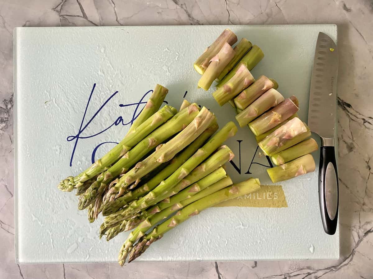 Cut ends to asparagus on a cutting board with a sanduko knife.