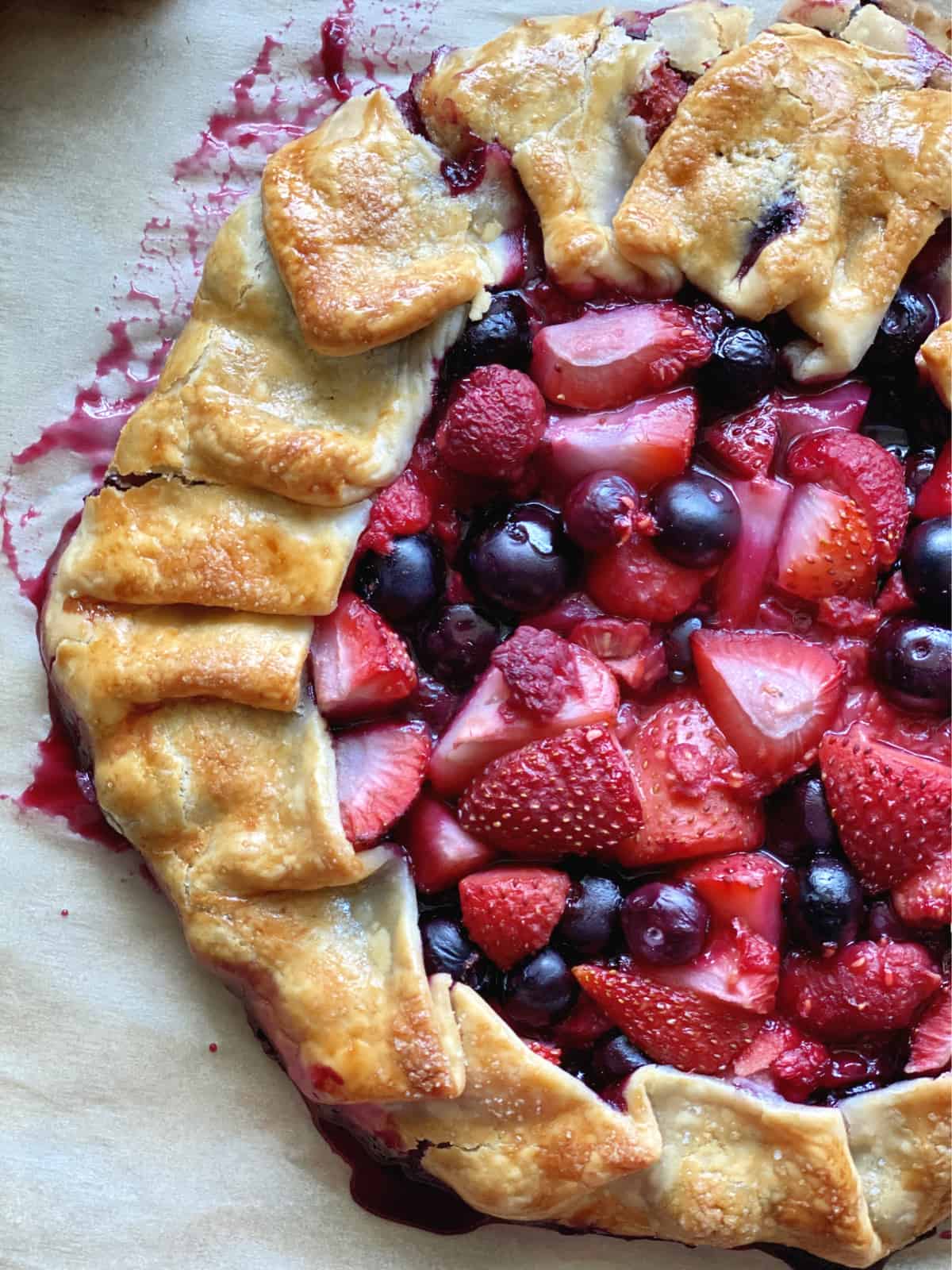 Top view of baked open pie crust with blueberries, strawberries, and raspberries. 