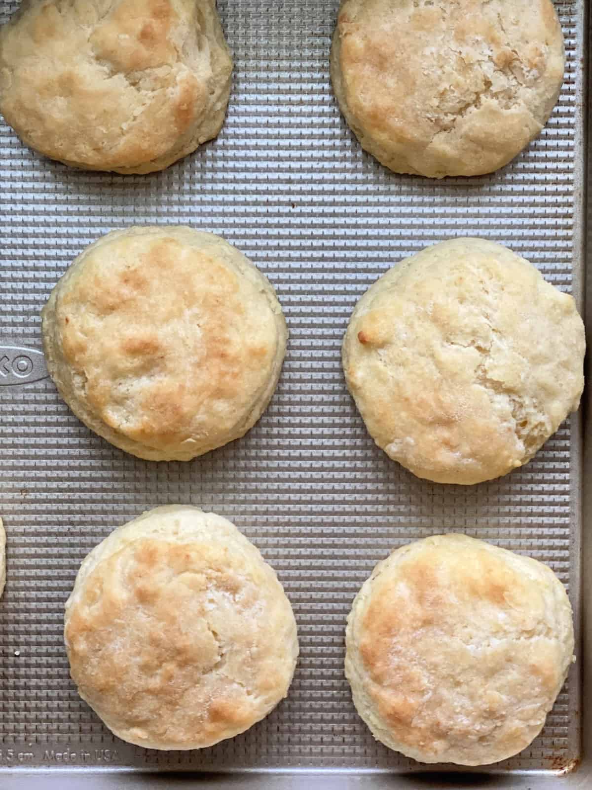 Top view of cooked biscuits on a golden baking sheet.