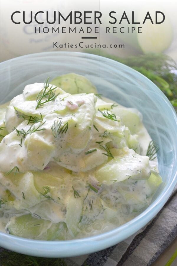 Close up of blue bowl with thinly sliced cucumbers in white cream sauce with text on image for Pinterest.