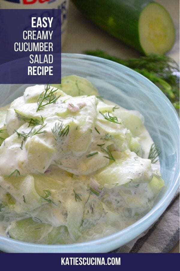 Close up of thinly sliced cucumbers in cream sauce with dill and text on image for Pinterest.
