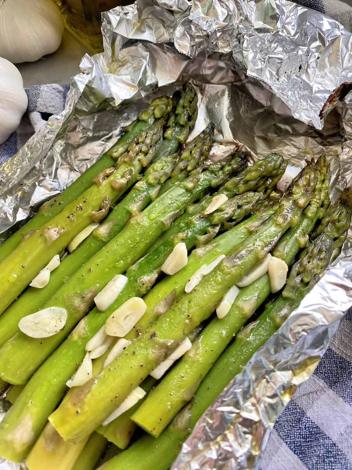 Top view of cooked seasoned asparagus with sliced garlic in foil.