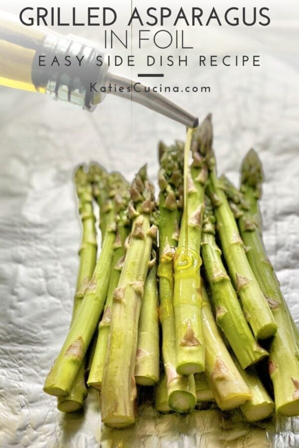 Olive oil pouring from spout on to asparagus on foil.