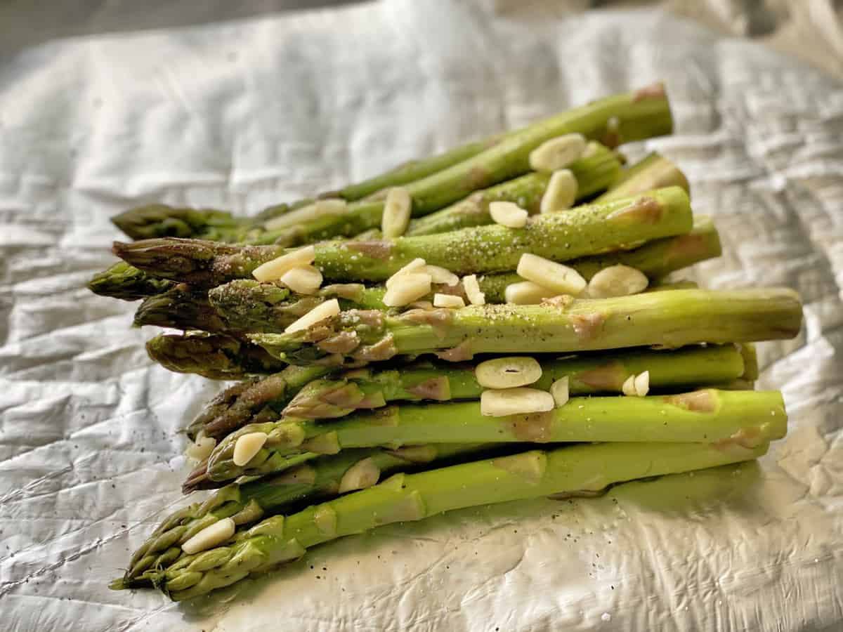 Cut asparagus laying on foil with sliced garlic on top.
