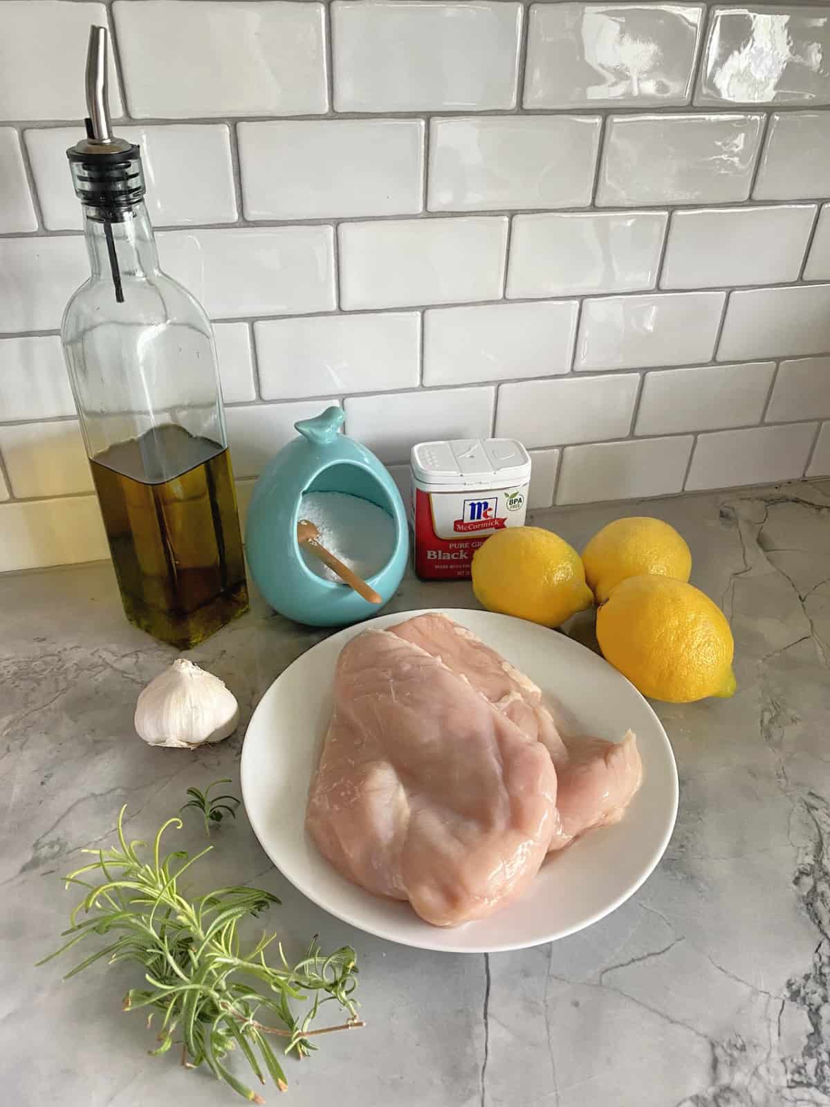 Ingredients: raw chicken breast, lemon, garlic, rosemary, olive oil, salt, and pepper.