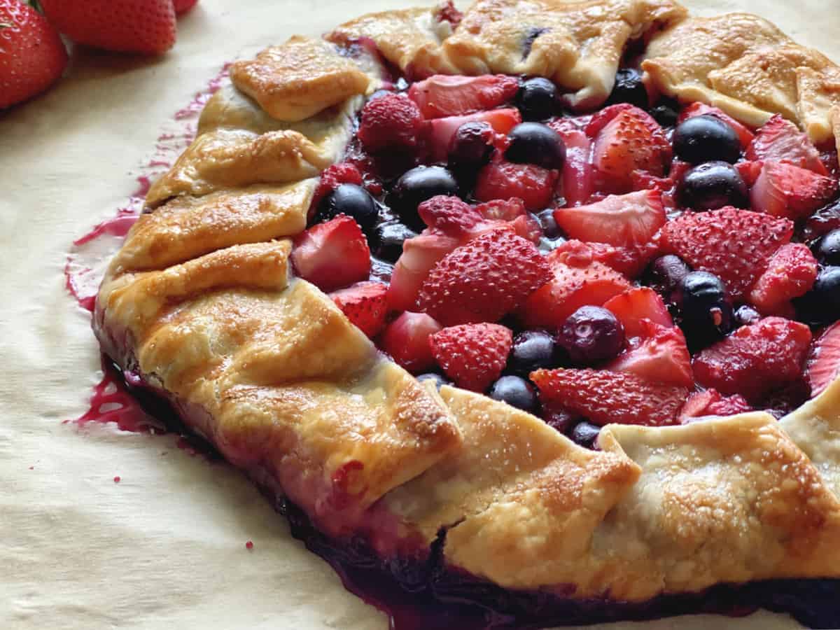 Side view of baked crostata with strawberries, raspberries, and blueberries. 