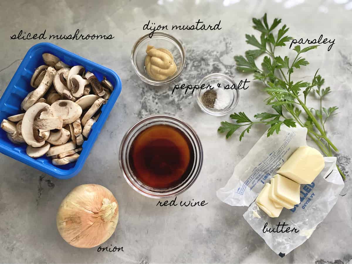 Ingredients on marble counter: mushrooms, onions, red wine, mustard, parsley, butter.