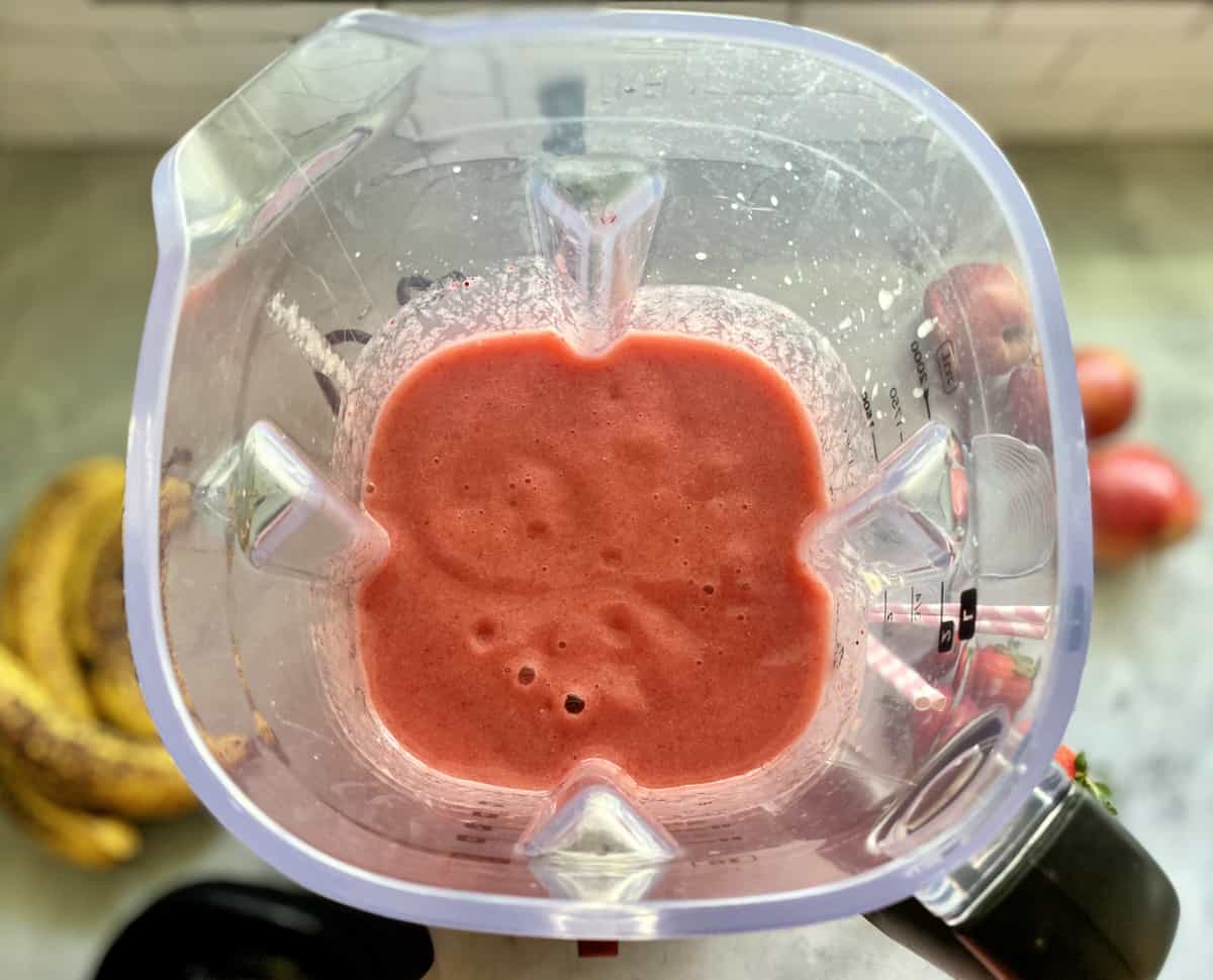 Top view of a pink blended smoothie in a blender.