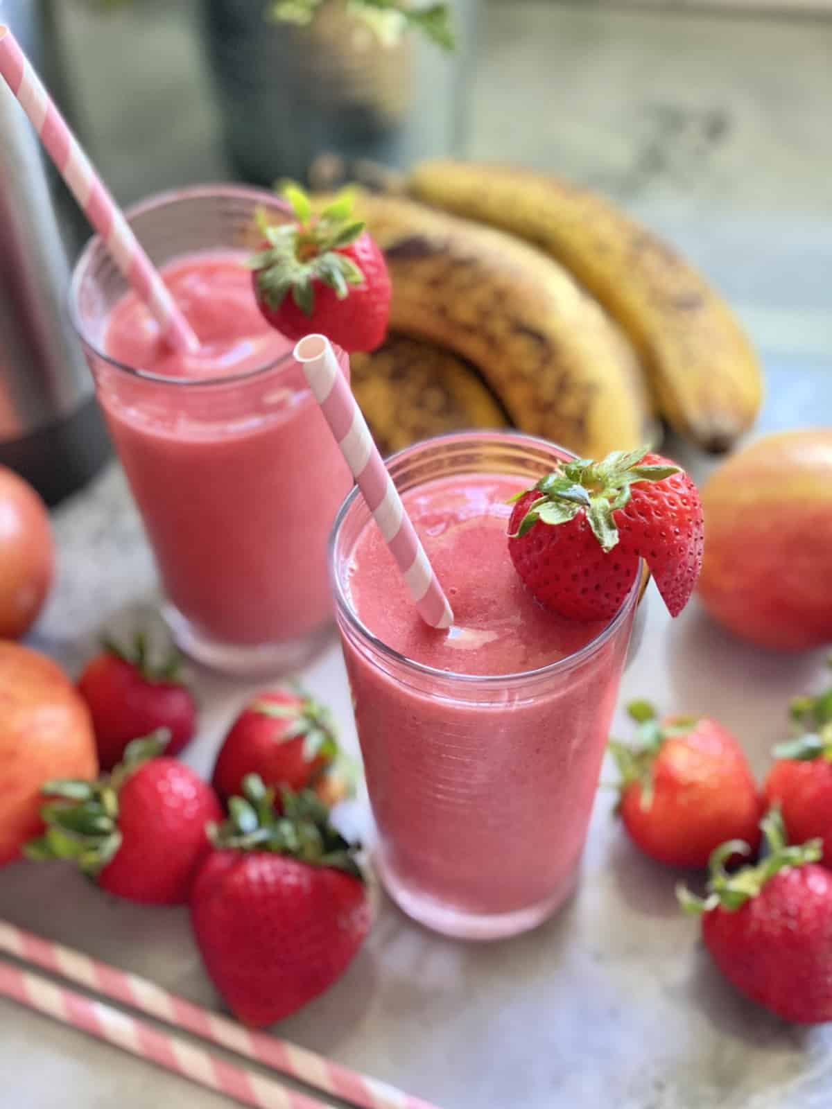 Overhead view of a smoothies in a glass with a strawberry and paper straw.