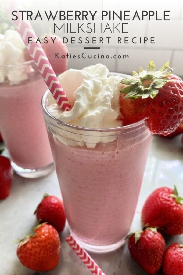 Glass of strawberry milkshake with fresh strawberries on counter with text.