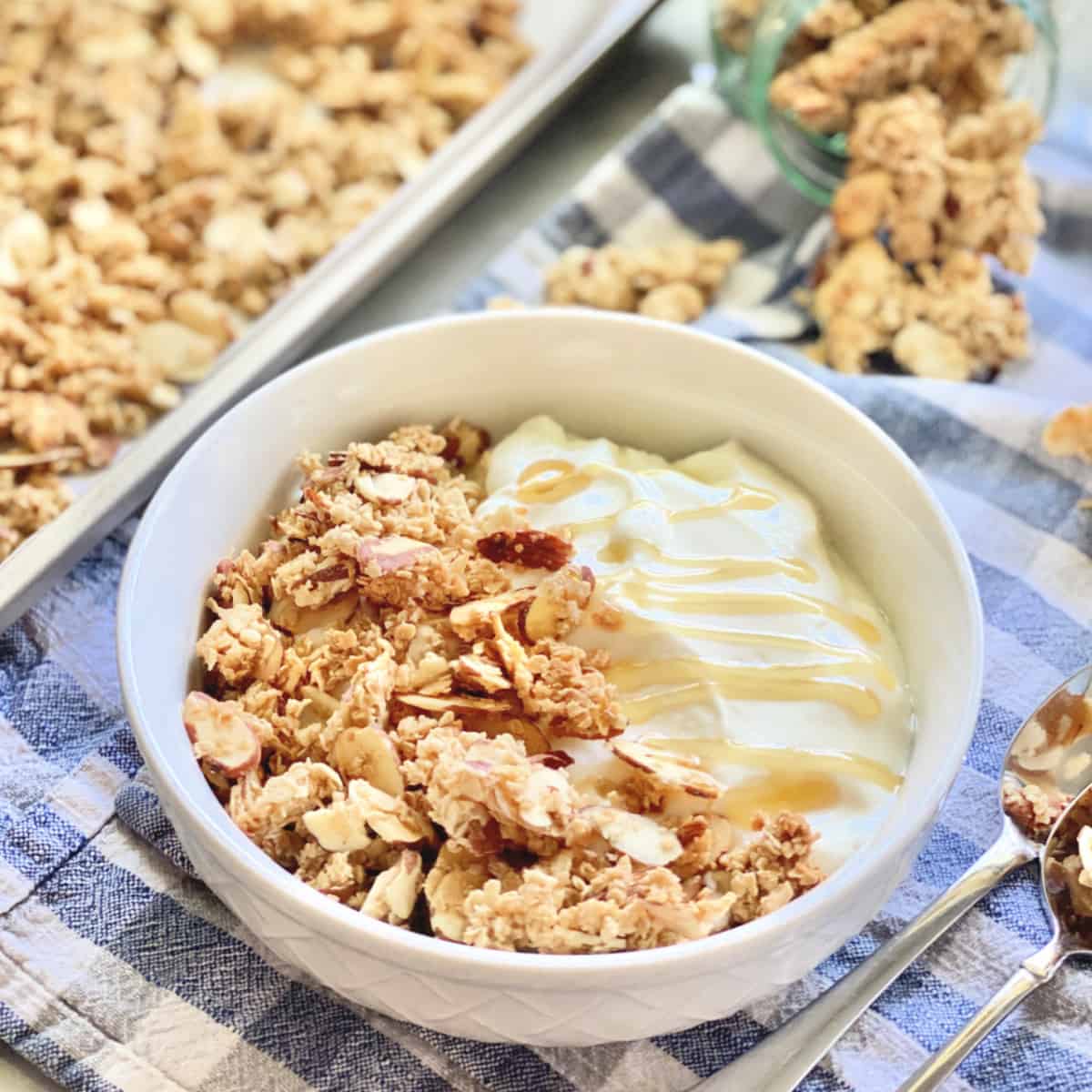 white bowl with yogurt, granola, and honey.