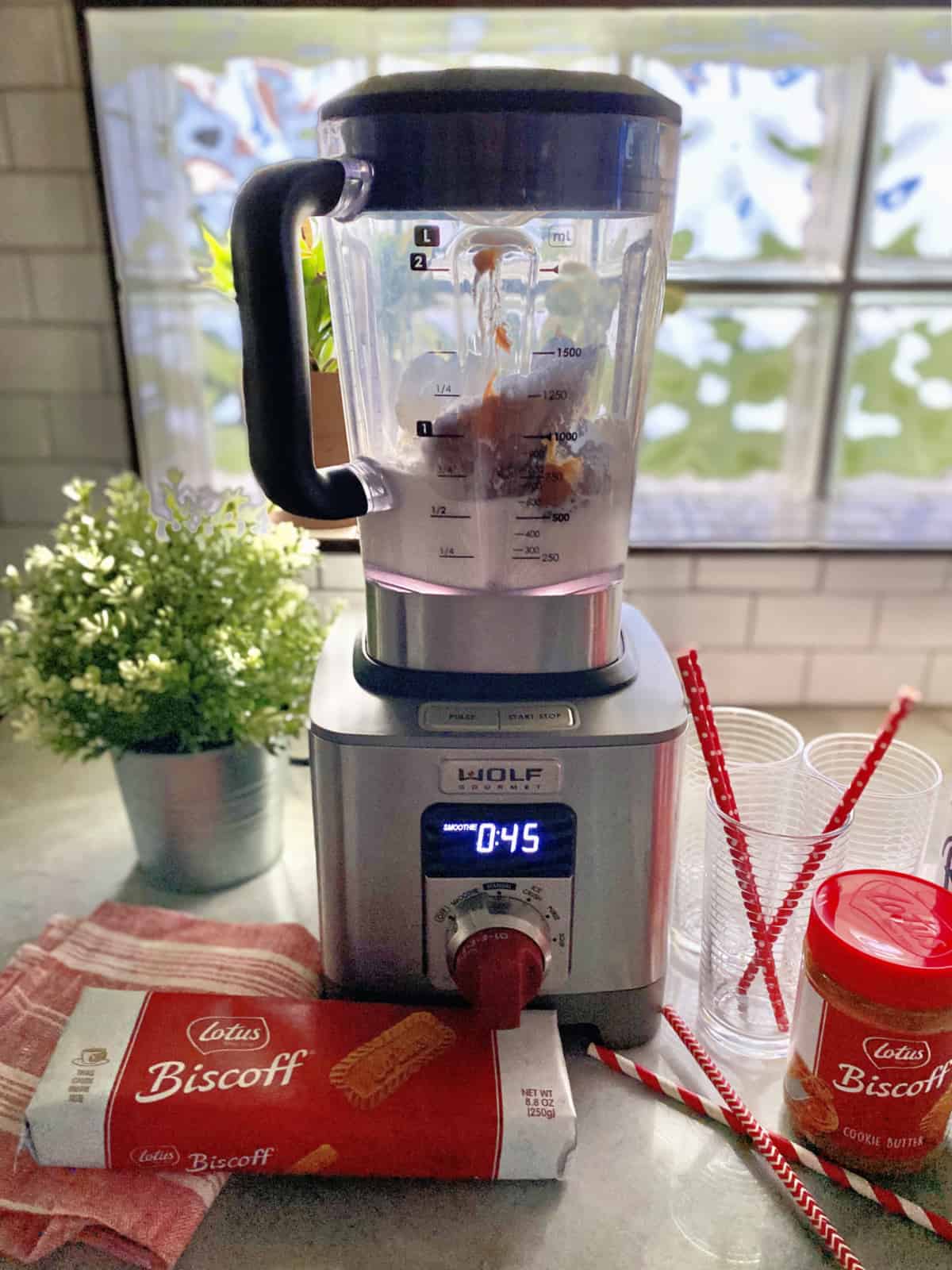 Blender set to to 45 seconds filled with whipped cream and cookie spread with cookies on counter.