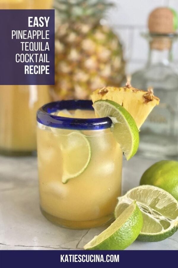 Close up of clear glass with blue rim filled with pineapple cocktail with text on image for Pinterest.
