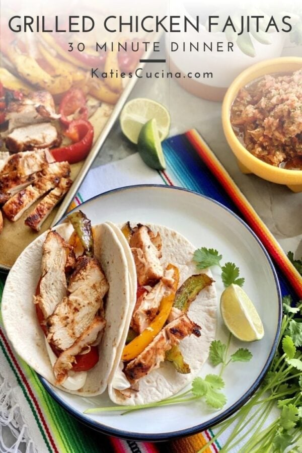 Overhead view of plated chicken fajitas in tortillas with lime with text on image.