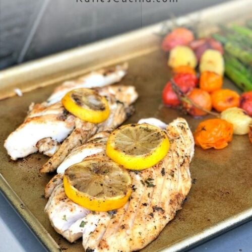 Gold baking sheet with cooked fish and veggies with text on image for Pinterest.