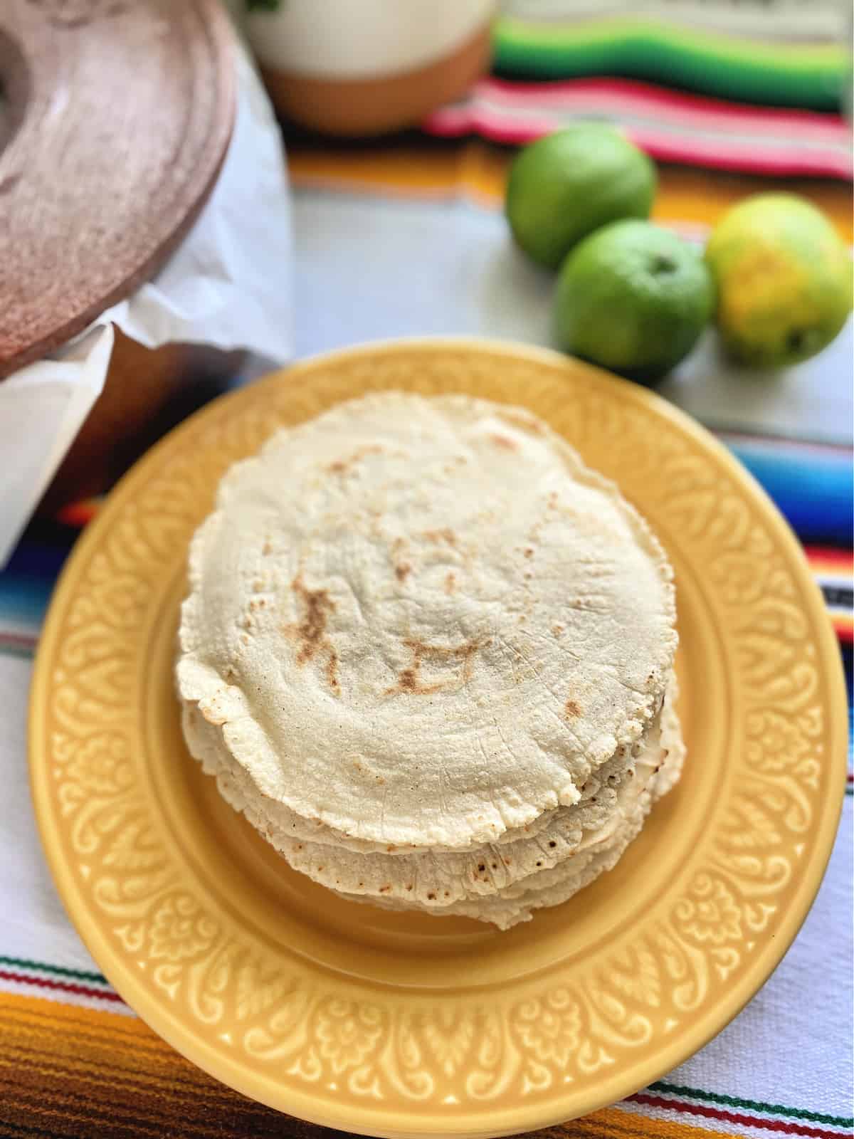 Yellow plate with corn tortillas stacked on top.