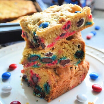 Three cookie bars stacked with red white and blue M&M's on a white plate.